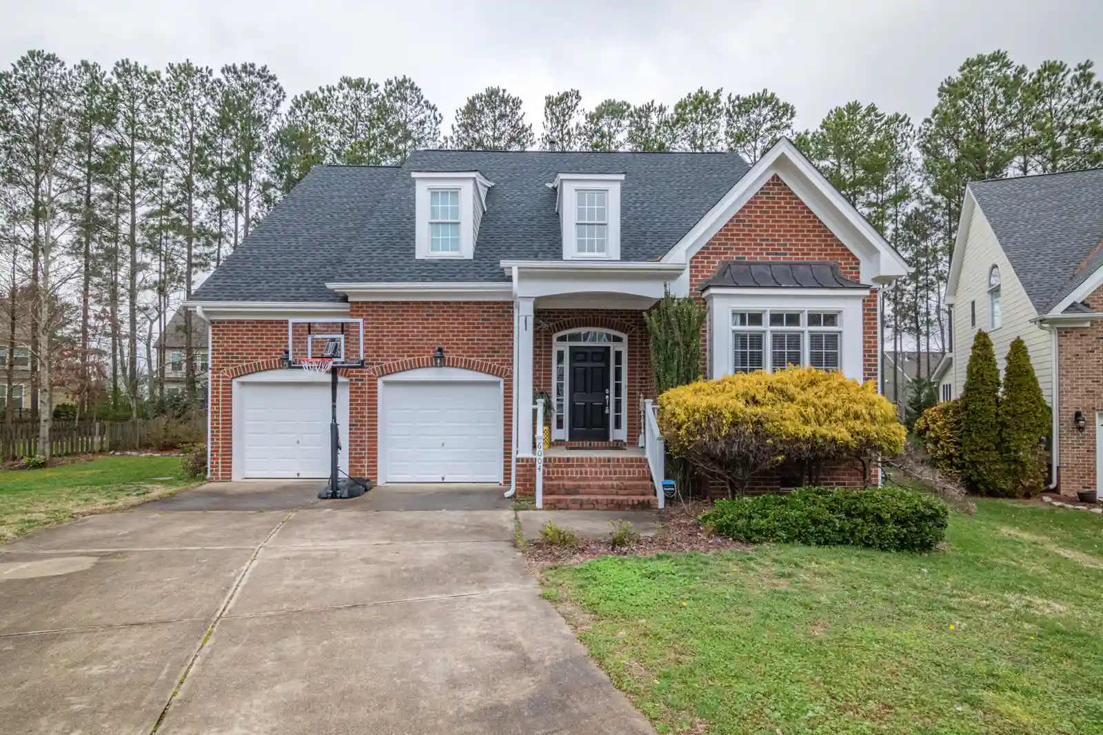 After — completed red brick home facade with white trim and landscaped front yard
