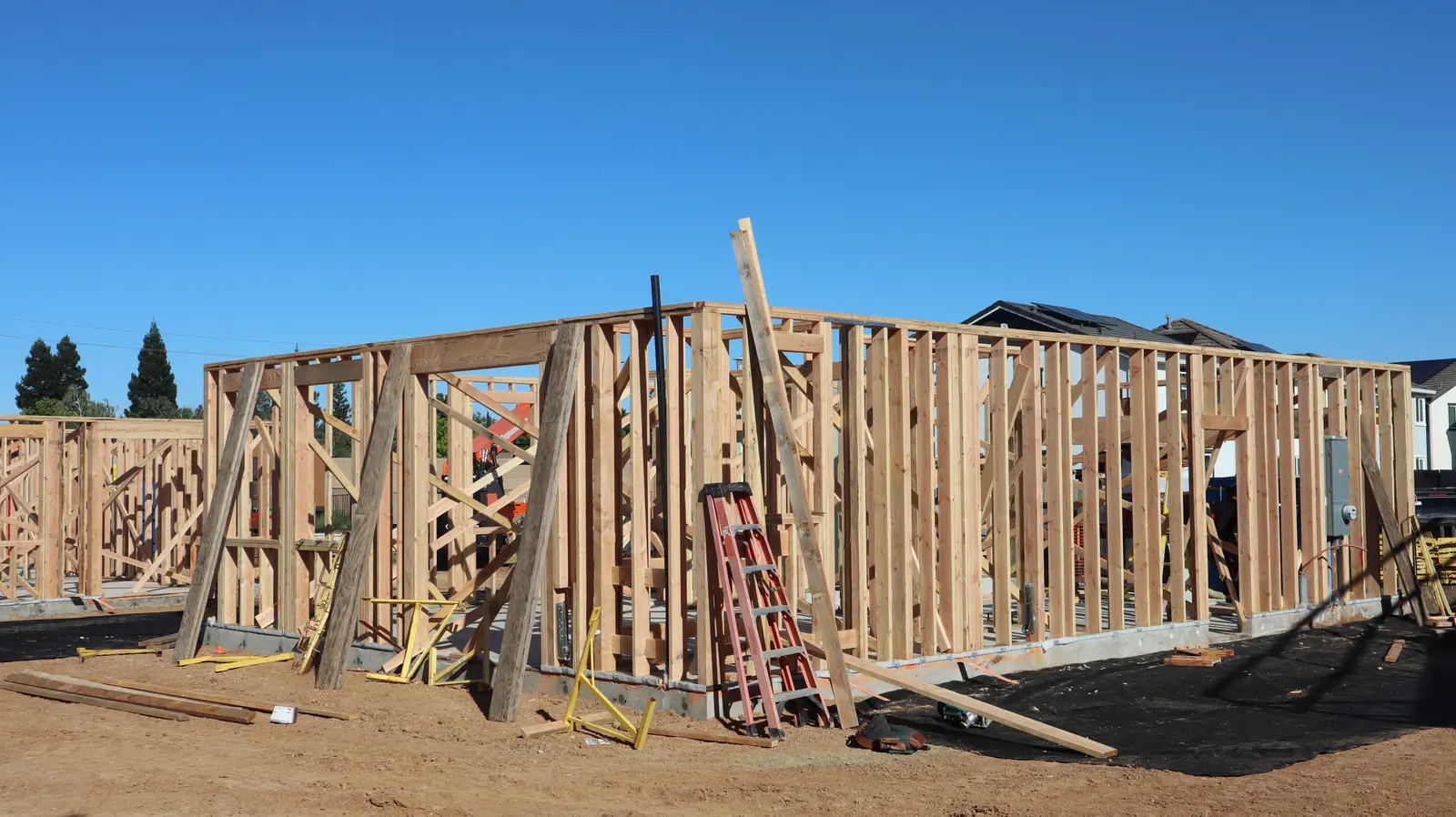 Before — open wood stud framing on a new home construction site, ready for the brick crew