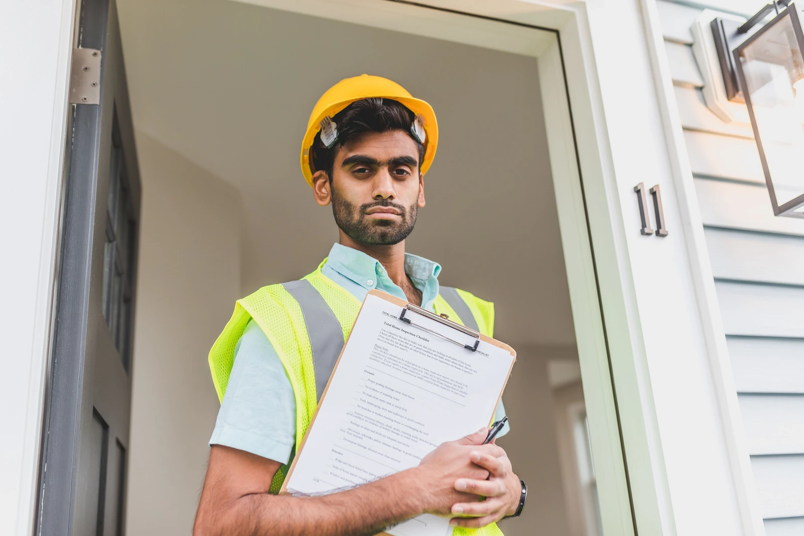 Our Mission — home inspector reviewing a total home inspection checklist at a new-construction entrance