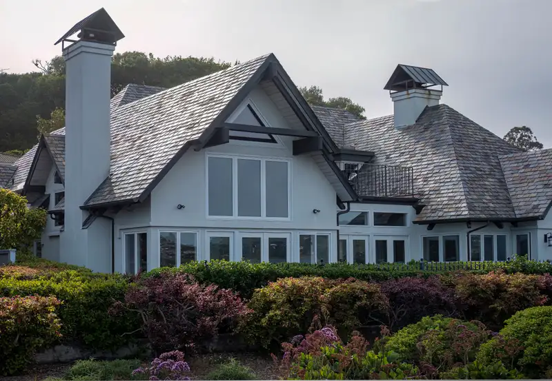 Finished masonry chimneys with metal caps on a shingle-style Chicagoland-style home