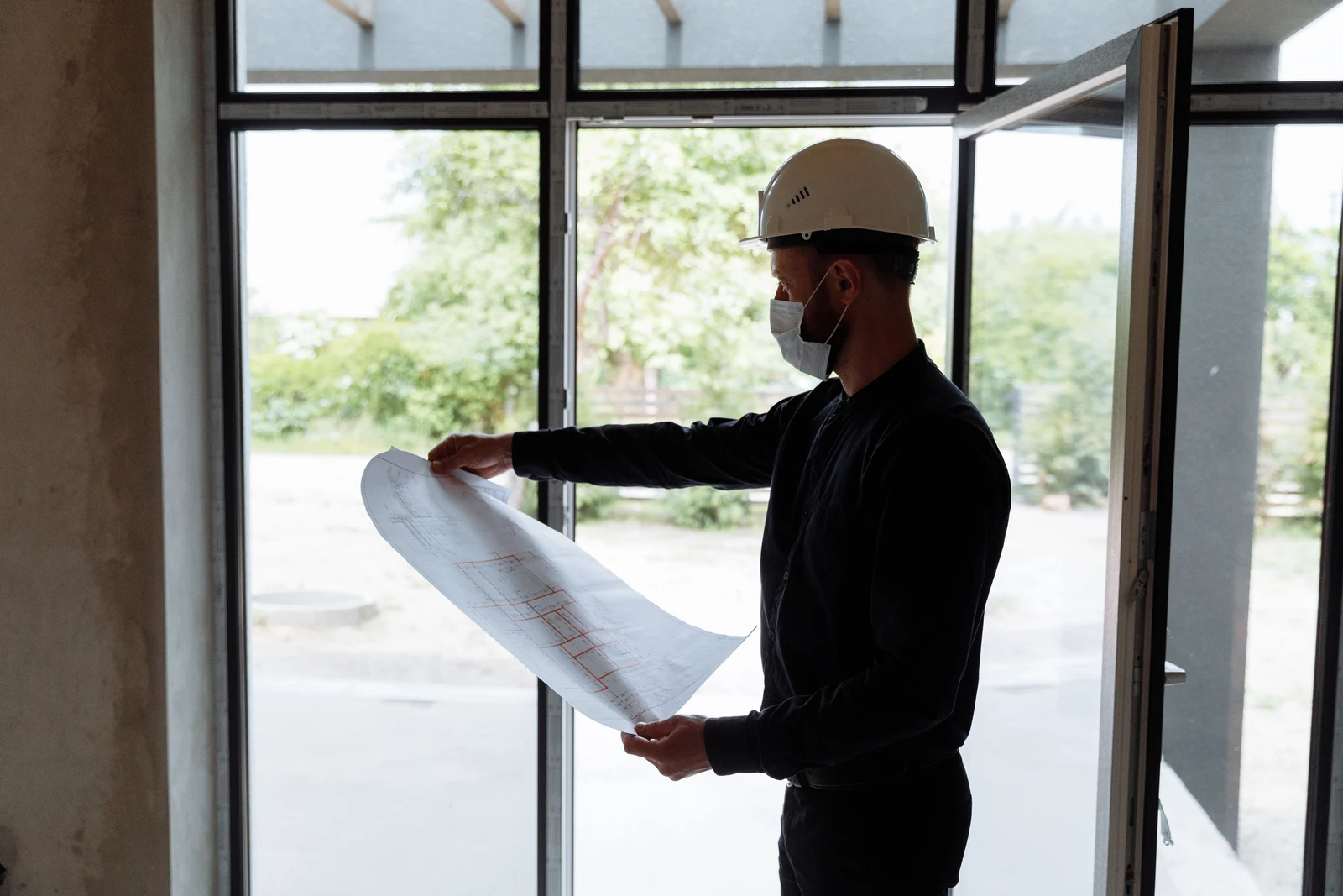Our Mission — engineer reviewing structural drawings on a new-construction site
