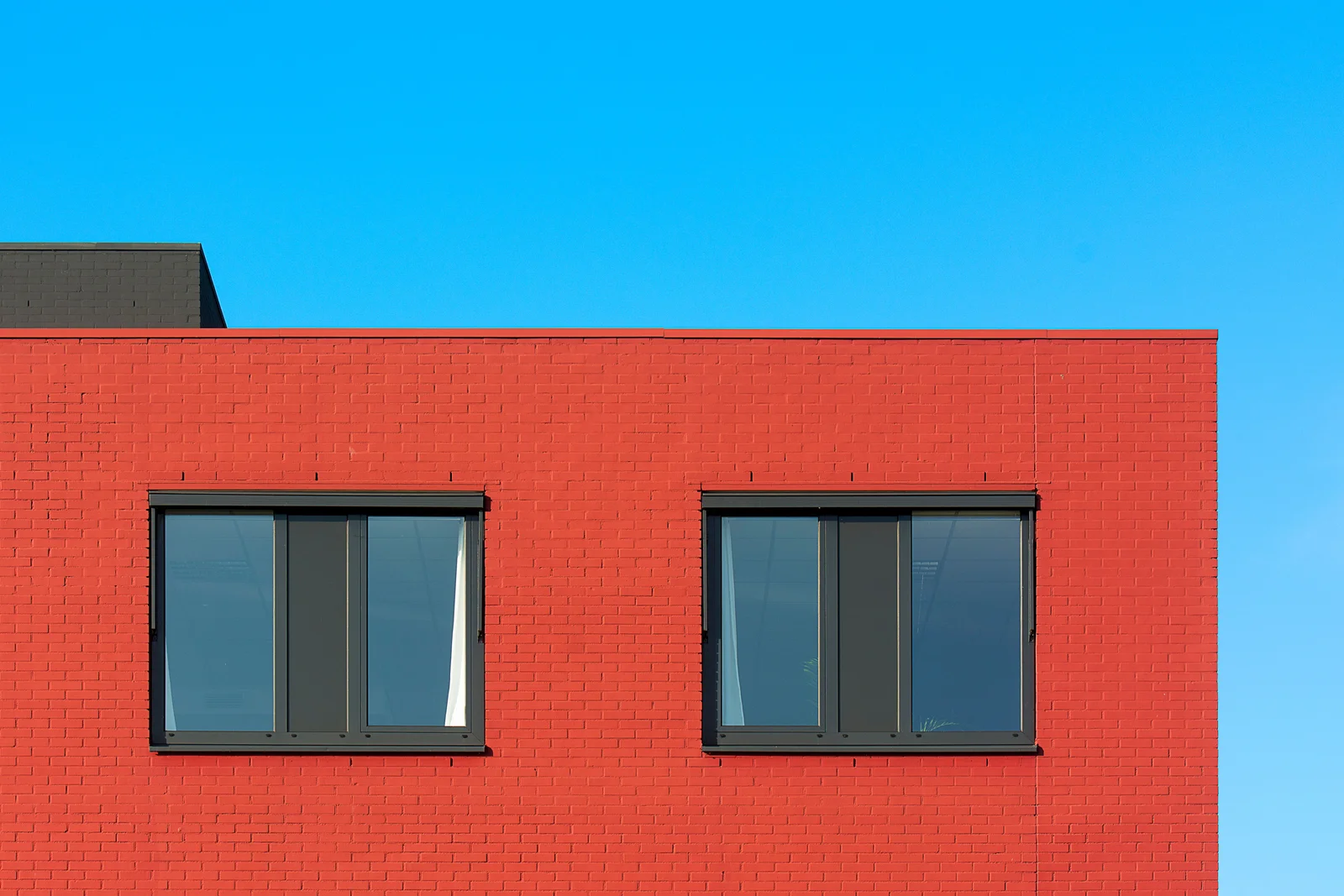 Clean modern red brick wall installation with new black-framed windows