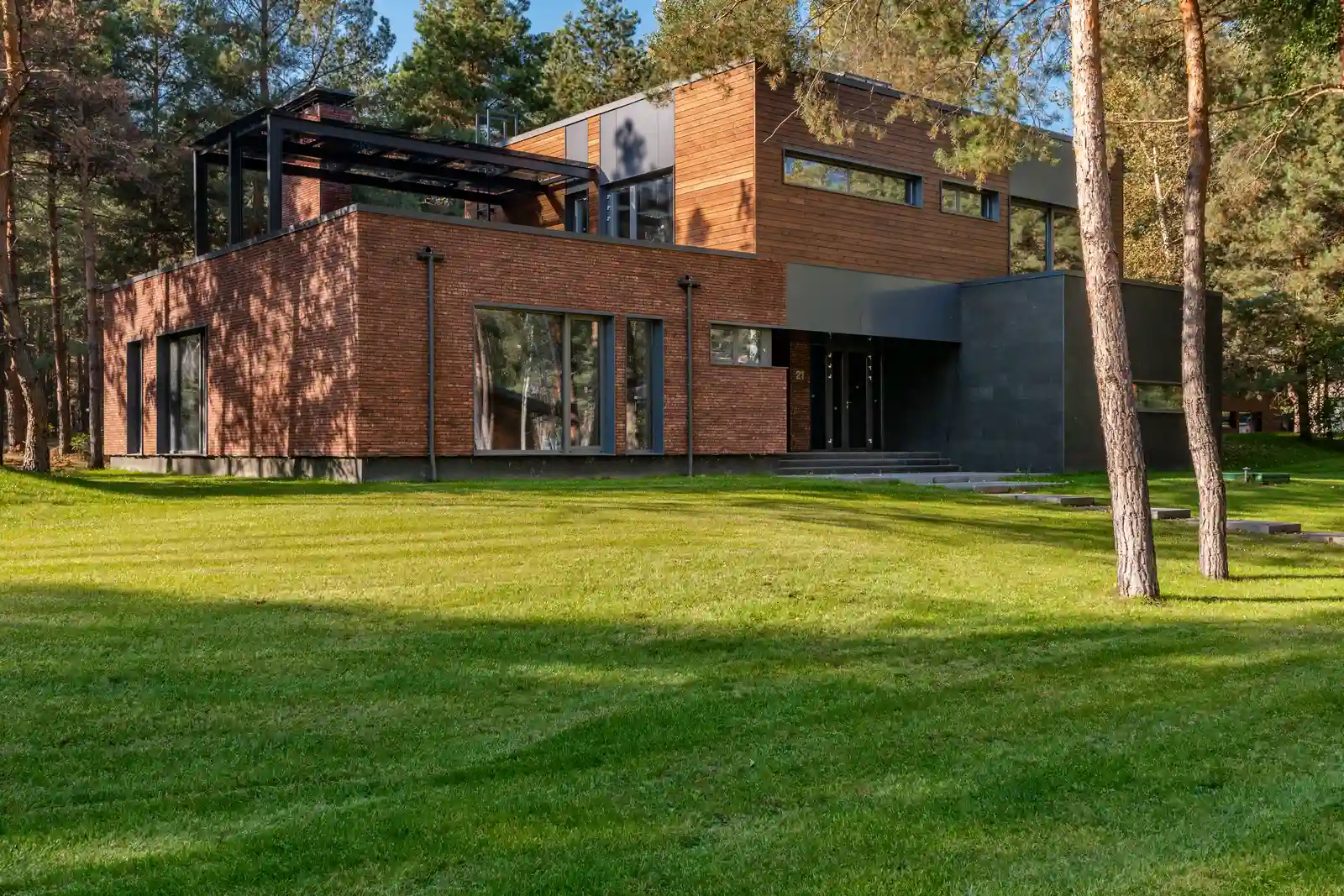 After — finished modern brick custom home facade with landscaped yard