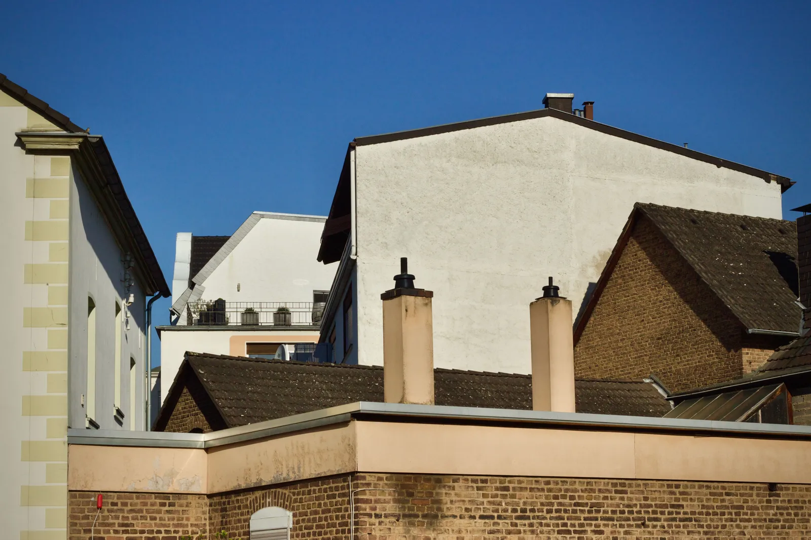 Brick chimneys on rooftops against a clear blue sky