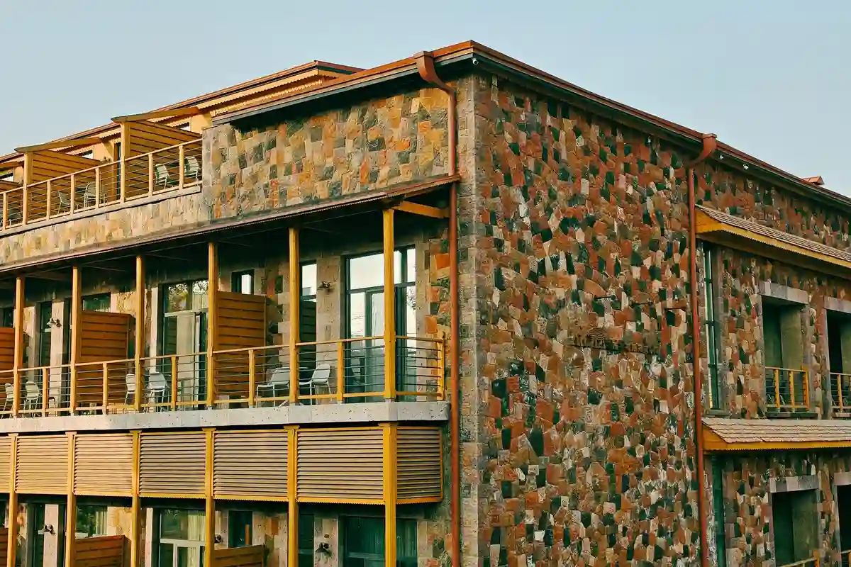 After: Primary facade — plain concrete wall clad with anchored natural stone veneer panels