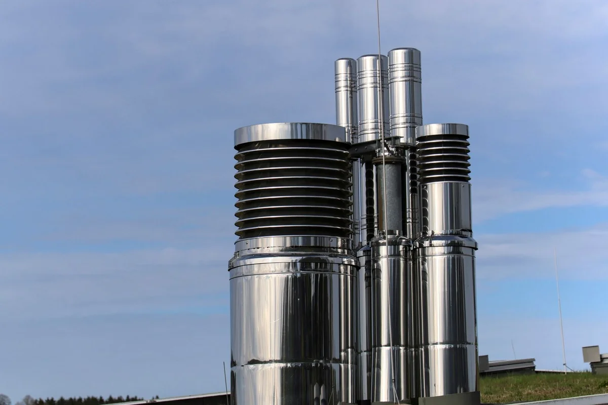 After: Chimney stack — new masonry chimney with poured crown, stainless cap, and woven flashing