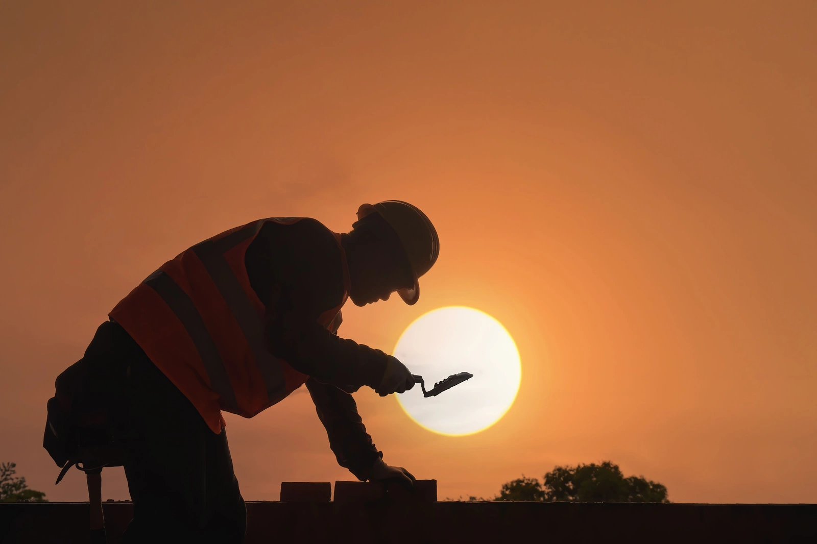 Our Mission — mason repointing brick with mortar and trowel at sunset